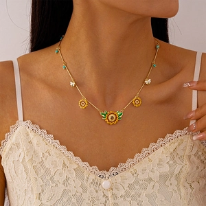 Detail shot of woman wearing gold sunflower and bee pendant necklace with blue beads