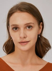 Macro view of gold U-shaped brass earrings with micro-inlaid cubic zirconia on model