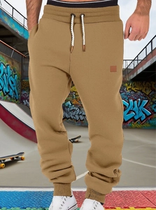 Detail of khaki jogger pants showing drawstring elastic waistband and street style logo patch