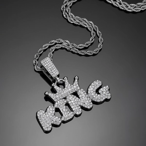 Macro shot of silver-colored KING pendant with crown and pavé crystals on rope chain