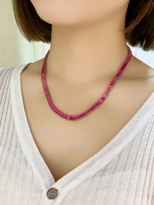 Close-up of a silver tennis necklace with pink cubic zirconia stones on a model