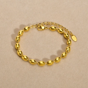 Detailed macro view of the K18 engraved tag and golden oval bead chain bracelet link