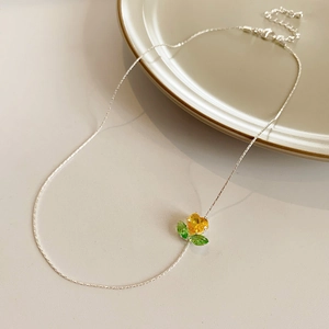 Detail der Silberkette mit gelbem Herz-Edelstein und grünem Blatt-Blumenanhänger