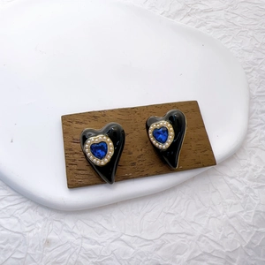 Elegant gold plated heart earrings with blue gemstone and pearls on a wooden block