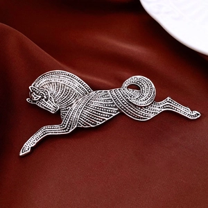 Macro shot of vintage silver running horse brooch with detailed texture on red satin