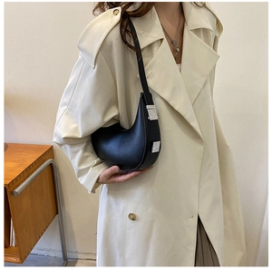 Minimalist black crescent shoulder bag with silver hardware on model in a stylish coat