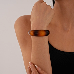 Close-up of model wearing chunky amber acrylic irregular open cuff bracelet