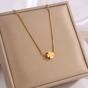 Macro shot of gold four-leaf clover heart pendant necklace on a jewelry box surface