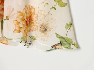 Détail d'une robe en mousseline élégante avec imprimés floraux, abeilles et papillons