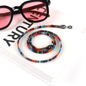 Close-up of bohemian woven cotton eyewear strap with adjustable rubber loops on book