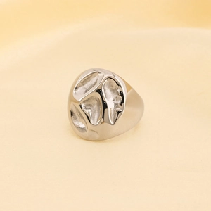 Macro detail of silver geometric lava ring with hammer textured surface on beige fabric