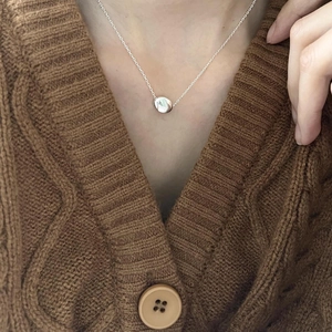 Close-up of minimalist S925 sterling silver geometric round pendant on a fine chain