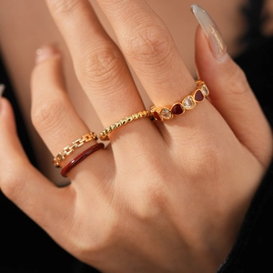 Close-up of a 4-piece vintage ring set with heart enamel and gold chain details on model