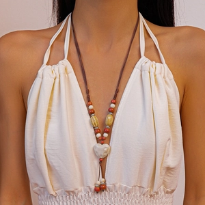 Gros plan d'un collier bohème avec perles en céramique rouges et blanches et cœur