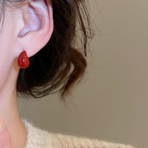 Close-up of red teardrop earrings on model with retro glossy resin finish