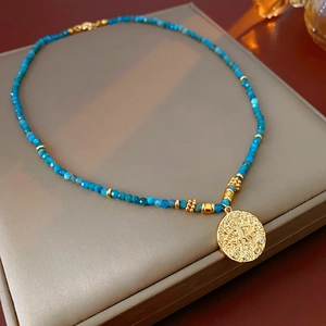 Macro view of blue faceted beads and gold evil eye pendant necklace on a jewelry box
