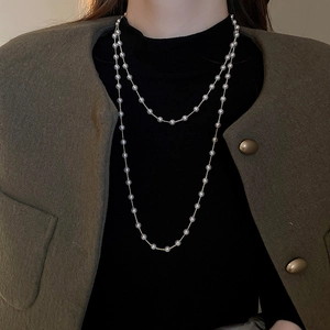 Détail d'un collier de perles superposées avec chaîne dorée sur mannequin