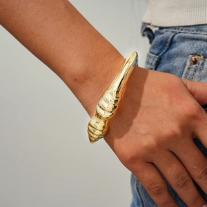 Detail of chunky gold irregular geometric bangle with textured surface on a wrist