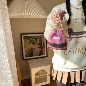 Detailed view of striped plush drawstring bag for cosmetics held in hand