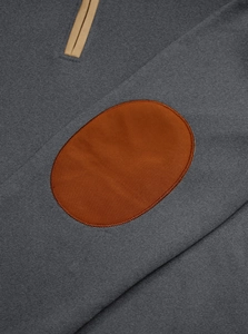 Detail of gray sweatshirt fabric with brown oval patch and khaki zipper trim accents