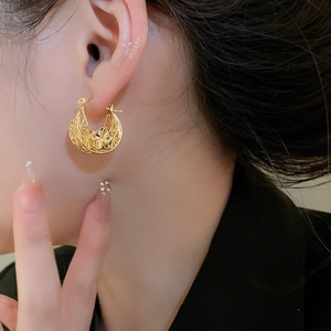 Detail of gold-plated hollow flower earrings showing intricate vintage metalwork