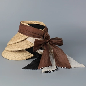 Close-up of straw sun visors with elegant pearl-edged chiffon bows and natural texture
