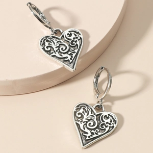 Vintage silver hollow heart earrings with intricate scroll patterns on round display
