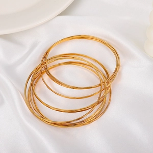 Close-up of stacked gold hammered bangles on white silk background showing fine texture
