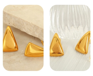 Close-up of golden geometric triangle stud earrings with a polished metallic finish