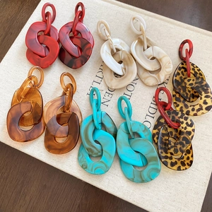 Close-up of lightweight acrylic drop earrings in red, marble white, and leopard print