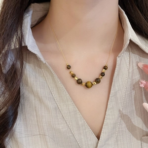 Detailed close-up of a 18K gold plated tiger eye stone necklace on a model's neck