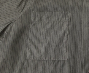 Close-up of a dark grey striped shirt featuring a bow detail and chest pocket