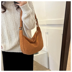 Caramel corduroy crescent shoulder bag with adjustable strap shown on a model
