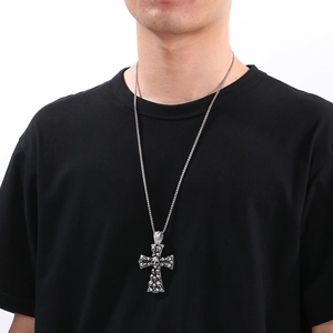 Detail of vintage silver skull cross pendant showing intricate reliefs on stainless steel