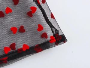 Detailed macro shot of black mesh fabric featuring vibrant red flocked heart patterns