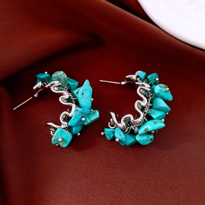 Macro shot of silver stud earrings with turquoise irregular stones on dark red silk background