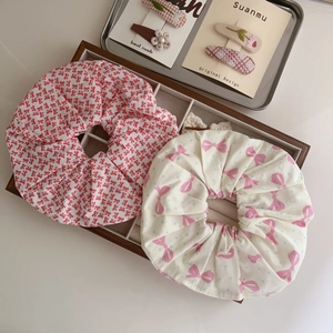 Detail view of cotton floral scrunchies with bow patterns in a rustic wooden tray