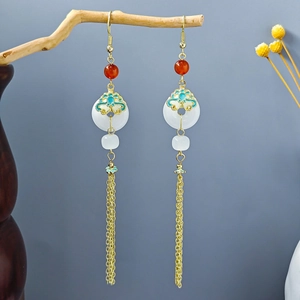Detail of vintage beaded earrings with white peace buckle and gold silk tassels