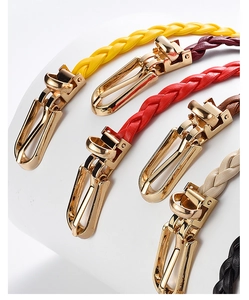 Detailed view of woven faux leather belts in multiple colors with gold metal ring buckles