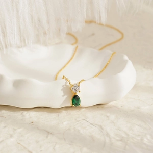 Macro detail of 18K gold-plated titanium necklace featuring a pear-shaped green gemstone