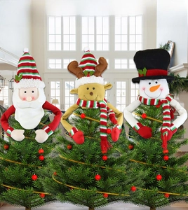 Detailed plush Santa, Elk, and Snowman Christmas tree topper hats in a cozy home setting
