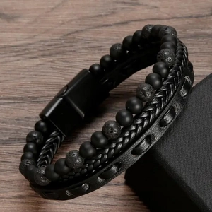 Detail of men's punk leather bracelet featuring lava stone beads and black magnetic clasp