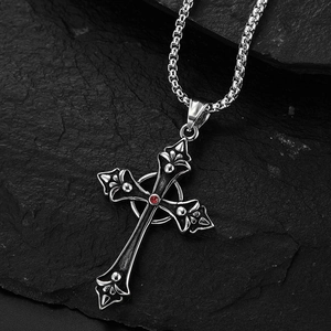 Vintage titanium steel cross necklace with garnet red stone on black rock background