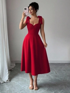 Detail van een rode zomerjurk met elegante strikbandjes en een slanke taille