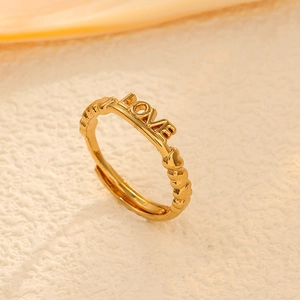 Detailed close-up of golden LOVE open ring featuring heart textures on stone surface