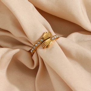 Gold-plated hug ring with sparkling zircons on a beige silk background