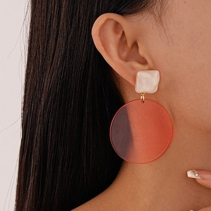 Close-up of model wearing geometric resin drop earrings in white and reddish-brown