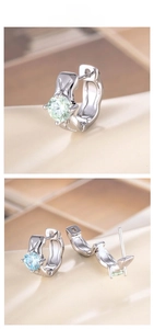 Detail of silver hoop earrings featuring a large light blue round-cut cubic zirconia