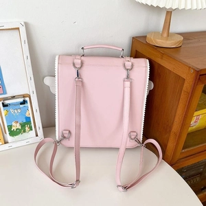 Close-up of pink backpack with white lace edges and decorative wings on the side