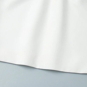 Detailed macro view of high-quality white twill woven fabric showing the garment hem texture